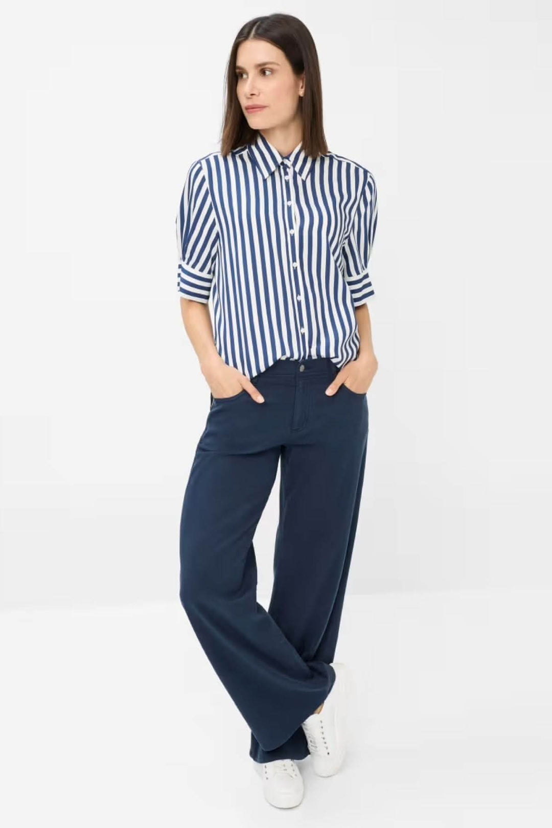 Femme portant un chemisier rayé et pantalon large, affichant un look chic et décontracté.