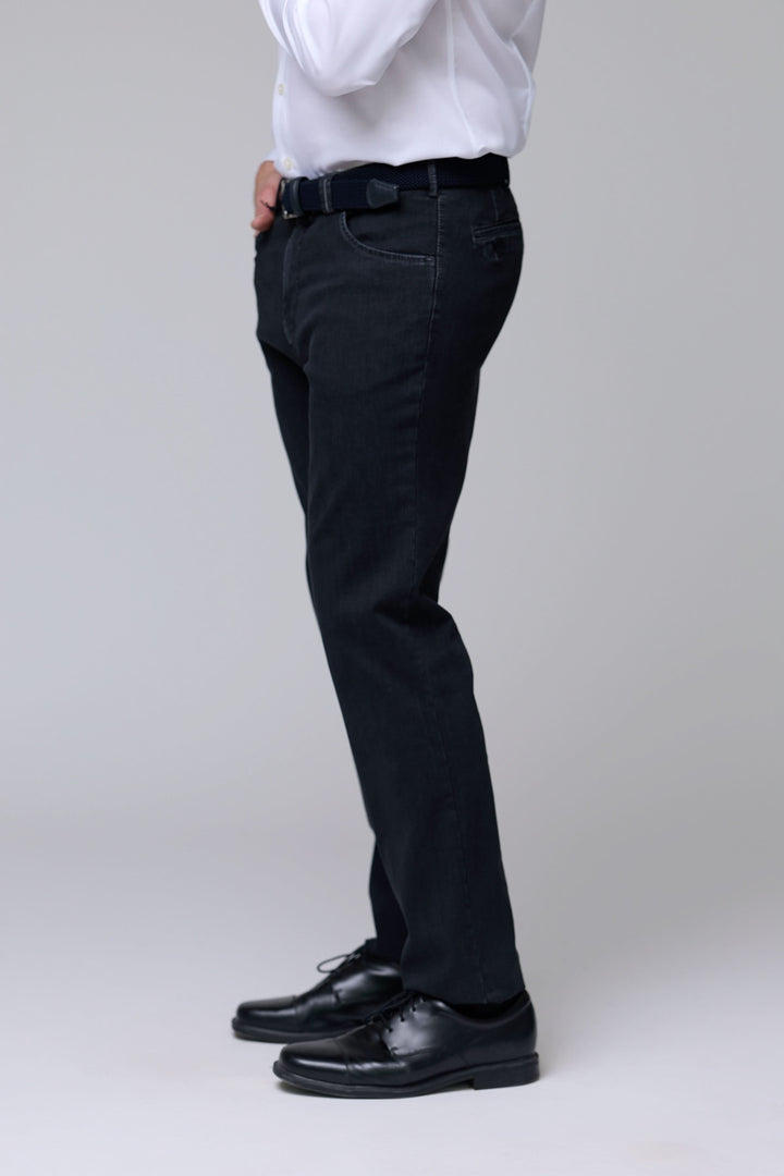Homme portant pantalon denim extensible noir avec coupe ajustée, idéal pour un style soigné. Décris moi le produit en français.