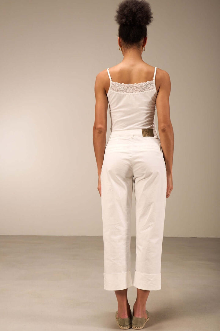 Femme vue de dos portant un pantalon droit 7/8 en coton léger, avec bas retroussés et top léger.