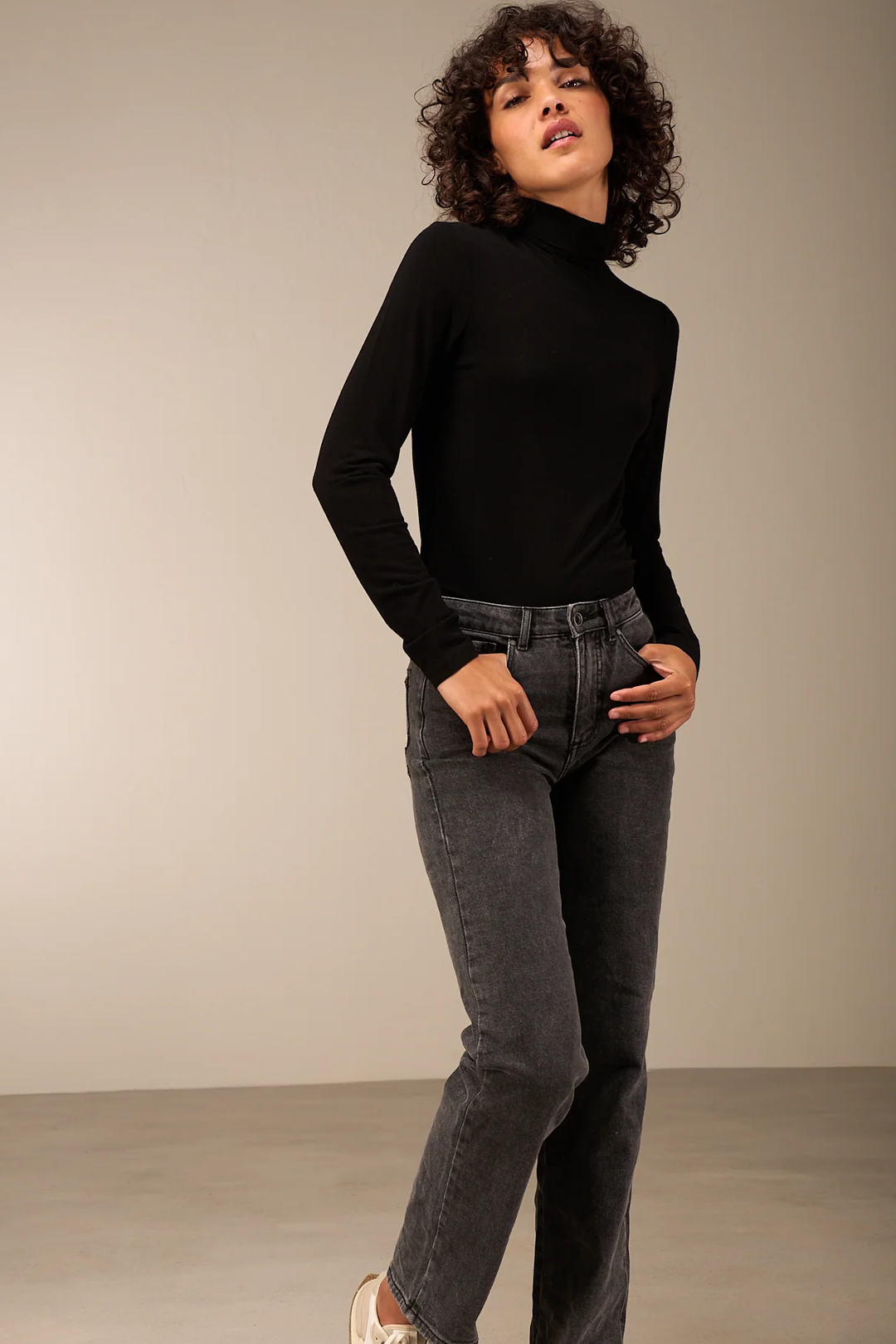 Femme portant un pantalon droit gris avec un chandail noir, illustrant un look moderne et polyvalent. Description du produit en français.