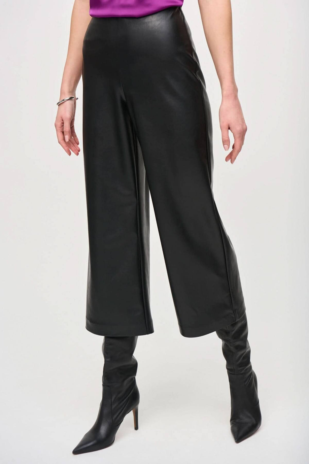 Pantalon 3/4 effet cuir souple, coupe large et taille haute, porté avec des bottines noires élégantes.