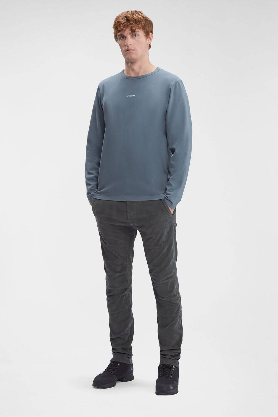 Homme en pantalon en velours côtelé gris et pull bleu, affichant une coupe moderne et décontractée.