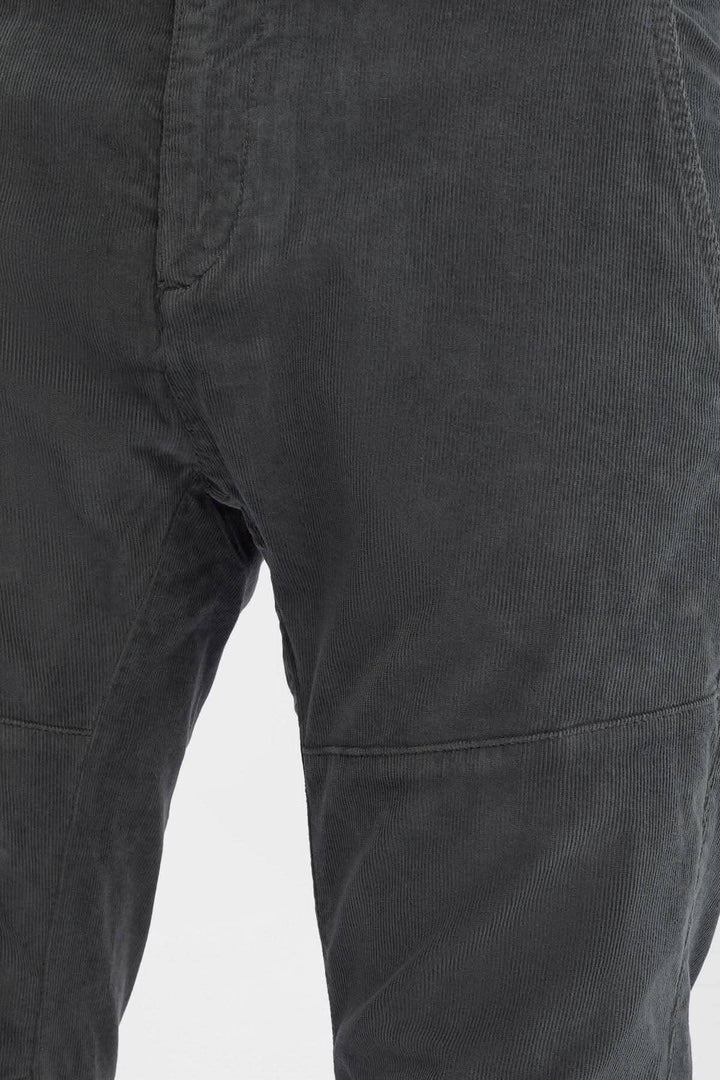 Pantalon en velours côtelé gris avec détails ergonomiques et braguette zippée.