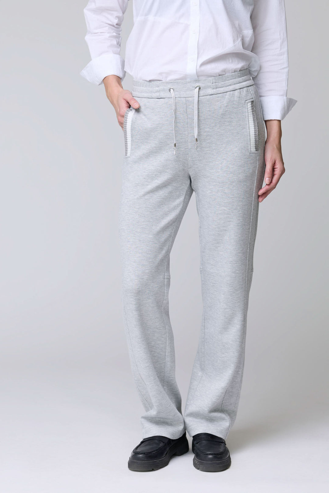 Homme portant un pantalon en jersey ajustable gris avec cordon et poches, idéal pour confort et élégance décontractée.