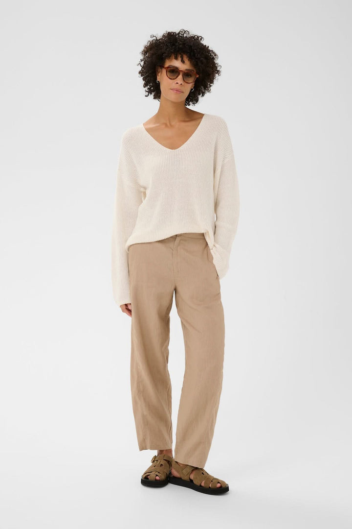 Pantalon en lin Atima beige porté avec une allure décontractée, mettant en valeur la coupe droite et le tissu léger pour un confort quotidien.