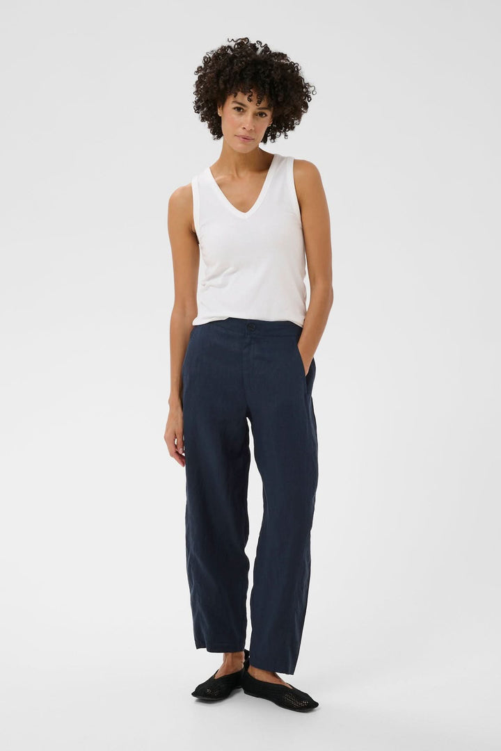 Femme portant un pantalon en lin Atima bleu marine avec coupe droite et taille régulière.