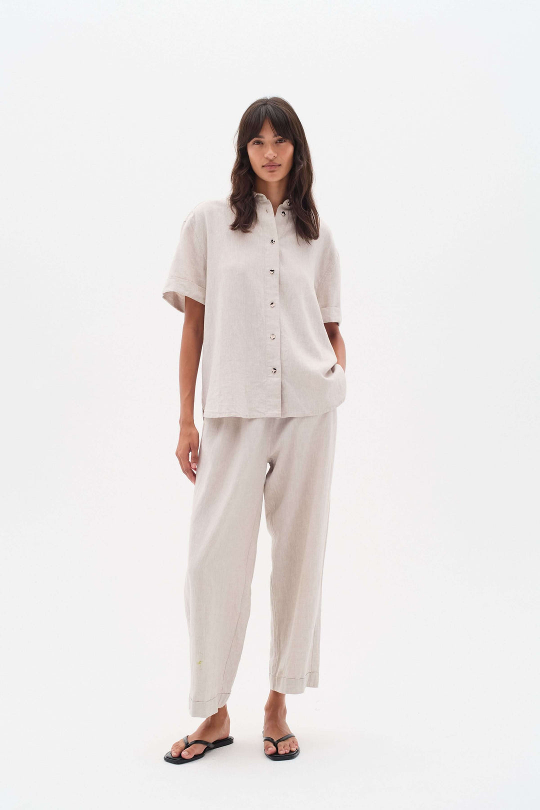 Femme portant un ensemble en lin avec chemise à boutons et pantalon large, style confortable et élégant.