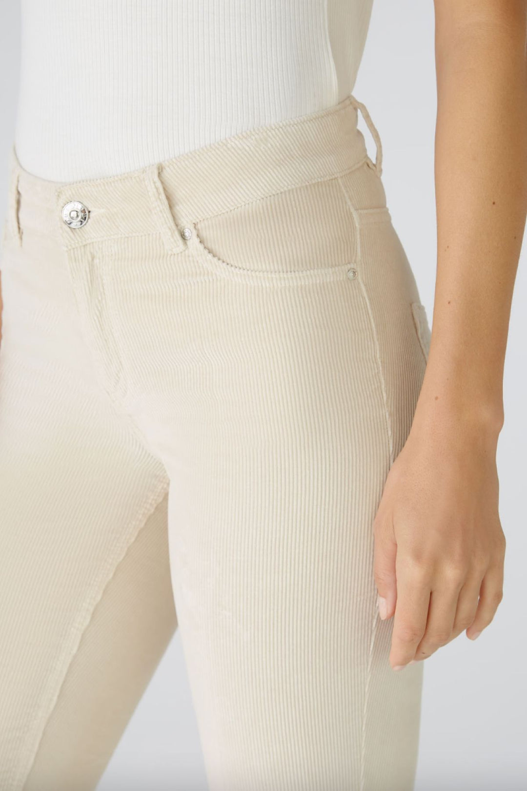 Pantalon en velours côtelé beige, coupe légèrement évasée, taille moyenne avec fermeture éclaire et bouton.