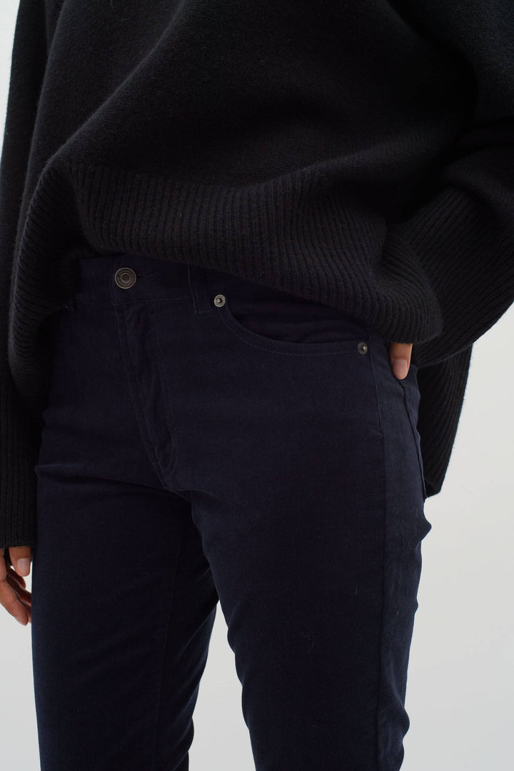 Pantalon en velours bleu marine porté avec un pull noir, idéal pour l'automne et l'hiver.