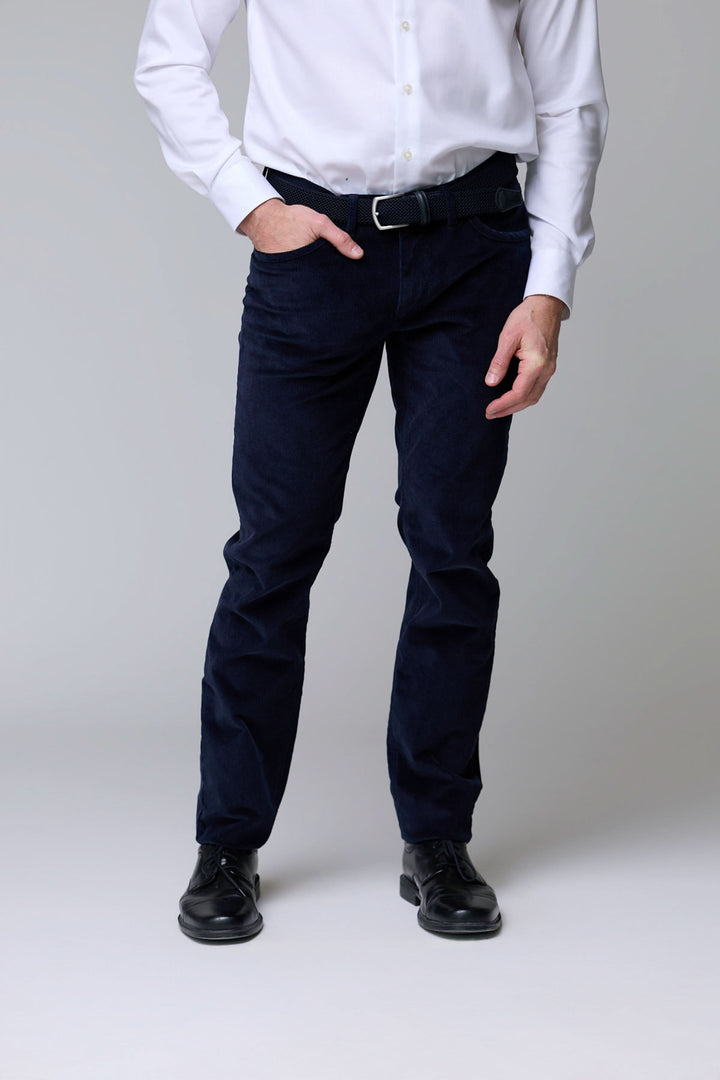 Homme portant un pantalon en velours côtelé bleu marine avec chemise blanche, coupe droite, pour élégance décontractée en saison froide.
