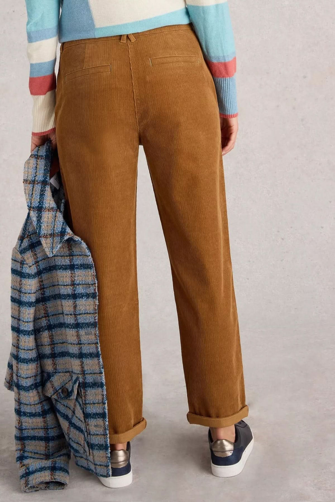Pantalon en velours côtelé brown, coupe droite, porté avec un pull coloré et une veste à carreaux.