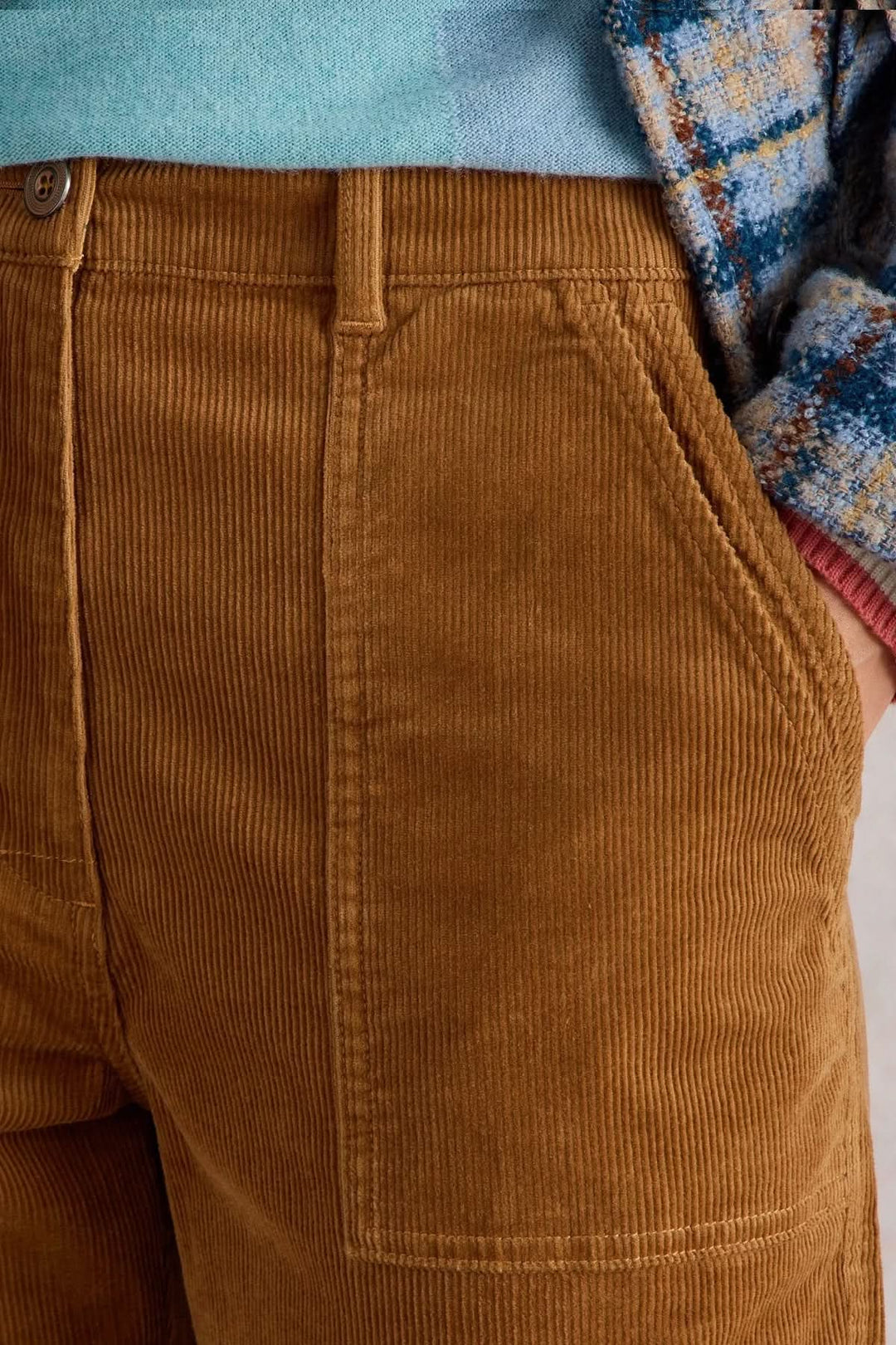Pantalon en velours côtelé marron avec poches et coupe droite, porté avec un pull coloré.