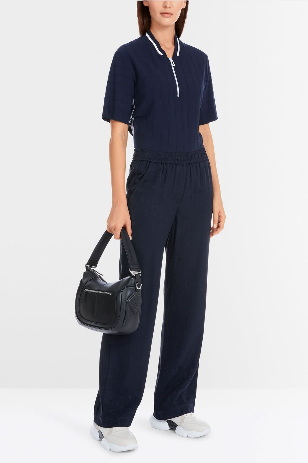 Femme portant une combinaison navy élégante avec poches, tenue décontractée et sac à main.