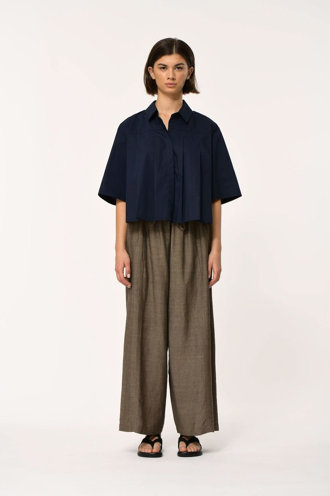 Femme portant un Pantalon fluide à coupe large JOAN avec chemise ample bleue, style moderne et décontracté.