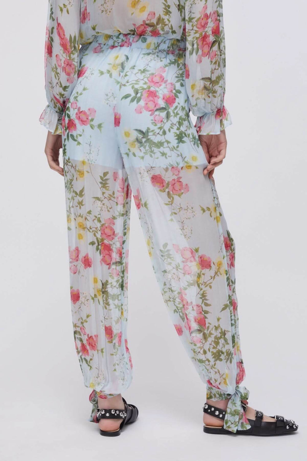 Vue arrière du pantalon fluide à imprimé floral, jambes longues et ourlets noués, tissu léger idéal pour l'été.