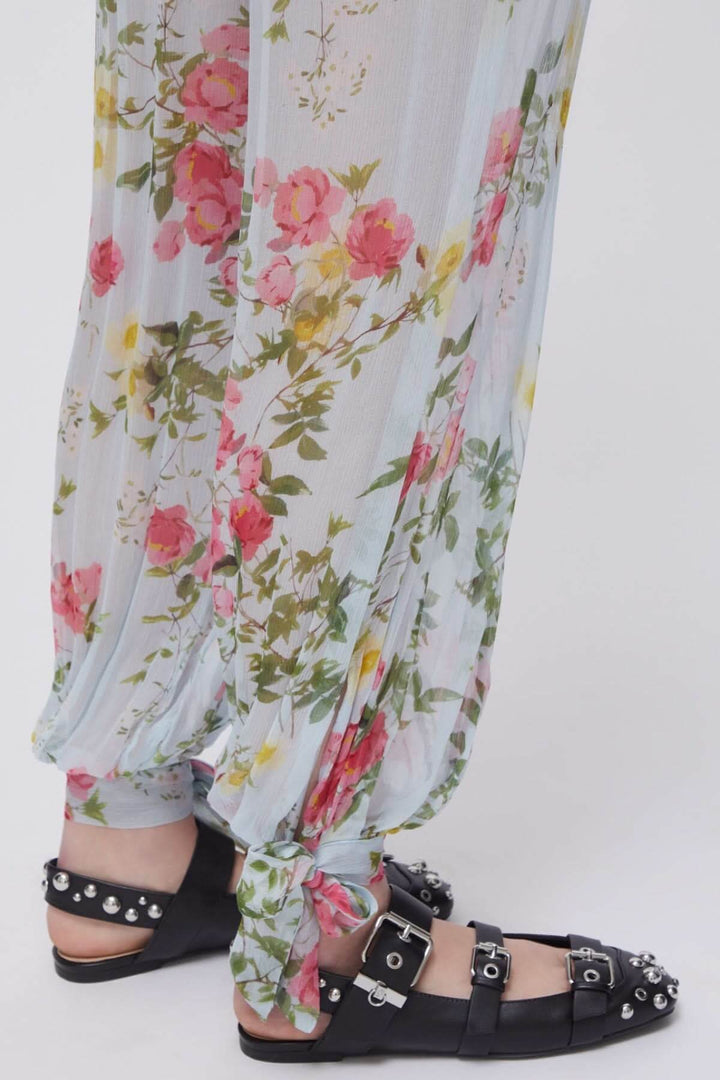 Pantalon fluide à imprimé floral avec ourlets noués et sandales noires cloutées, idéal pour l&