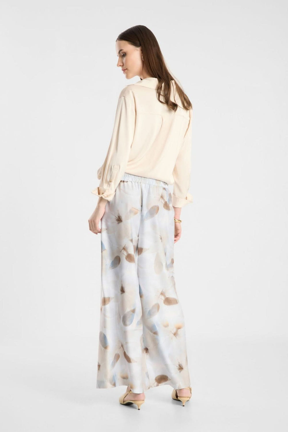 Femme portant un pantalon fluide imprimé à taille élastique, coupe large, tissu léger, look chic et décontracté.