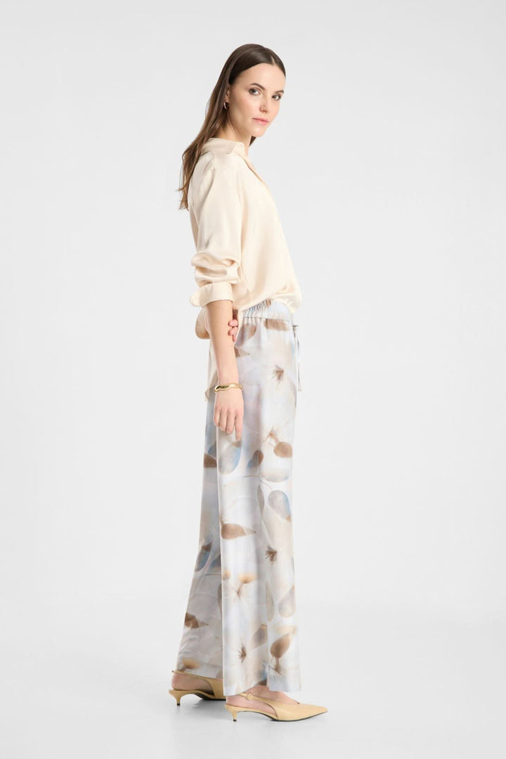 Femme portant un pantalon fluide imprimé à taille élastique avec coupe large et poches discrètes, style chic et décontracté.