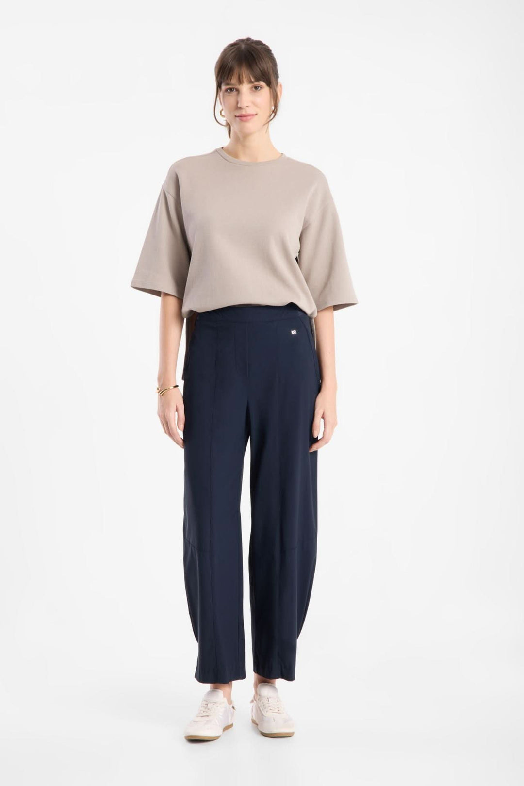 Femme portant un pantalon fluide à jambe large avec un haut beige, mettant en valeur une silhouette moderne et épurée.