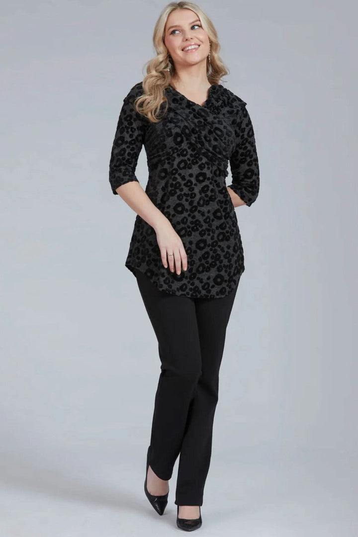 Modèle portant un pantalon habillé Tucker avec blouse noire à motifs, look chic et élégant.