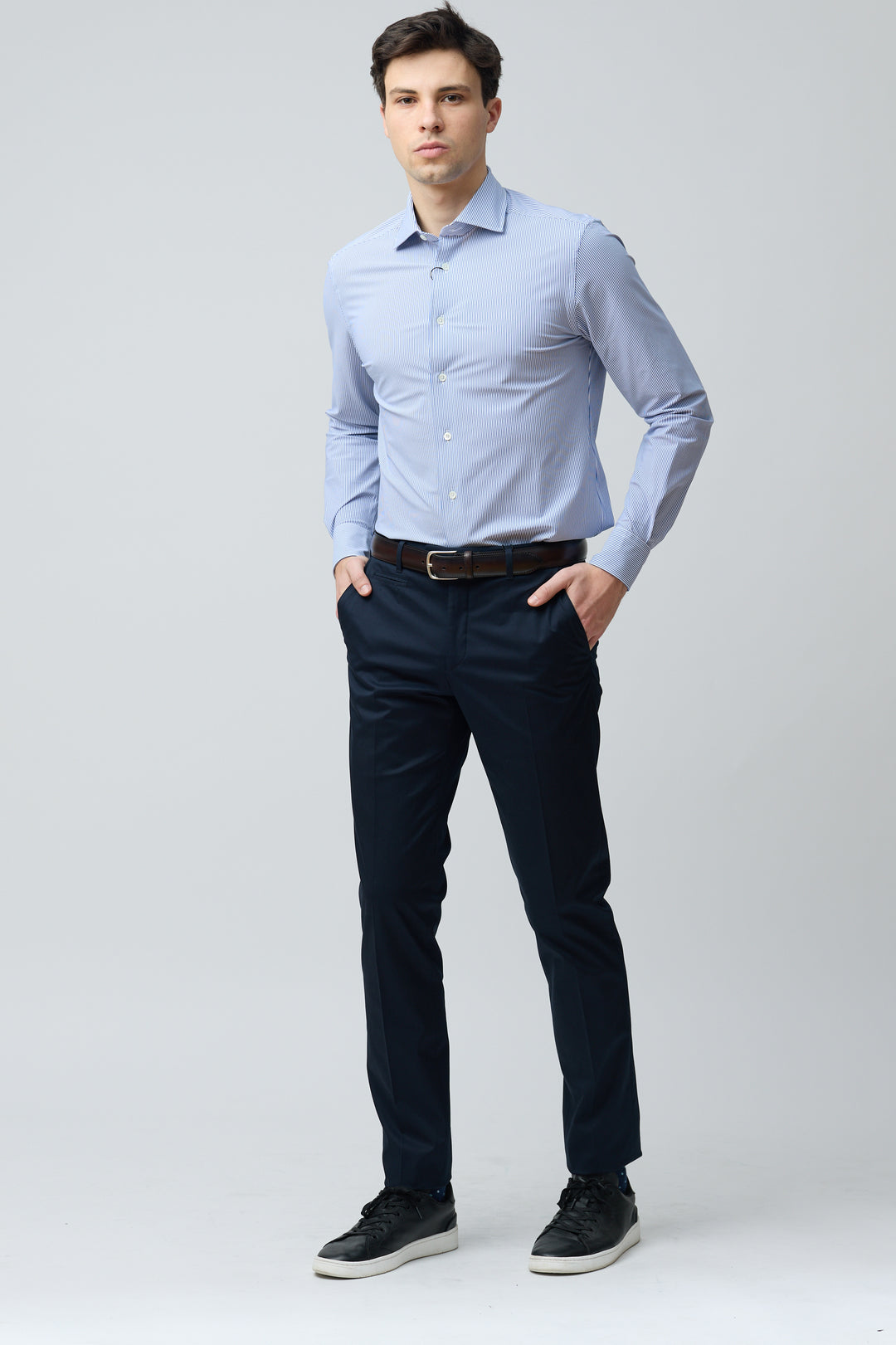 Homme portant un pantalon habillé coupe ajustée avec chemise bleue et ceinture brune, offre une silhouette nette et élégante.