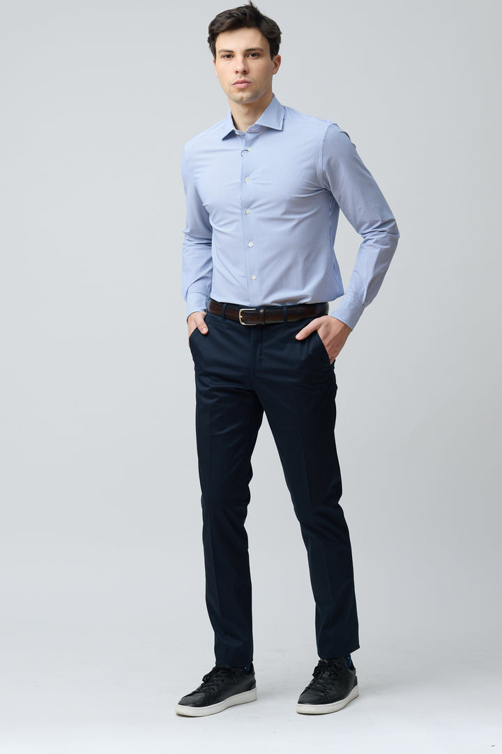 Homme portant un pantalon habillé coupe ajustée avec chemise bleue et ceinture brune, offre une silhouette nette et élégante.