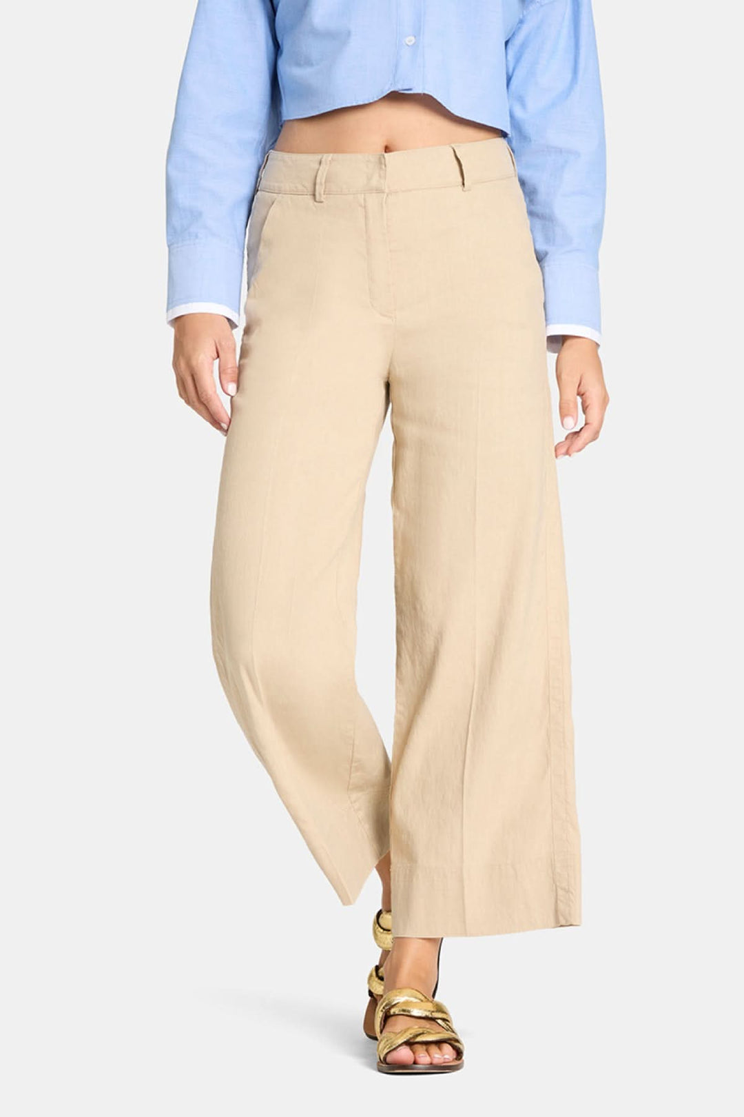 Pantalon à jambe large Cara en beige, coupe ample et fluide, porté avec une chemise bleue, offrant un style moderne et polyvalent.