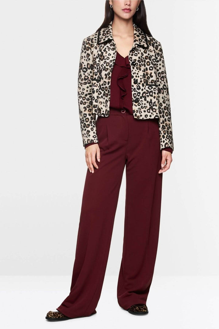 Femme portant un pantalon jambes larges fluide bordeaux avec une veste imprimée léopard. Pantalon élégant et confortable à taille haute.
