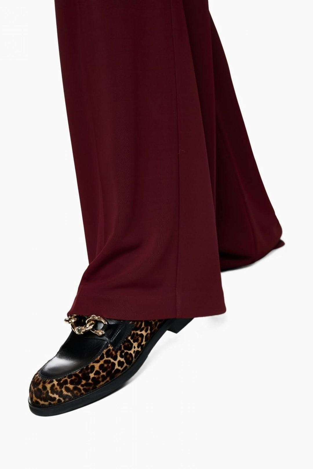 Pantalon jambes larges bordeaux avec détail chaussure mocassin léopard, offrant élégance et confort pour une silhouette structurée.