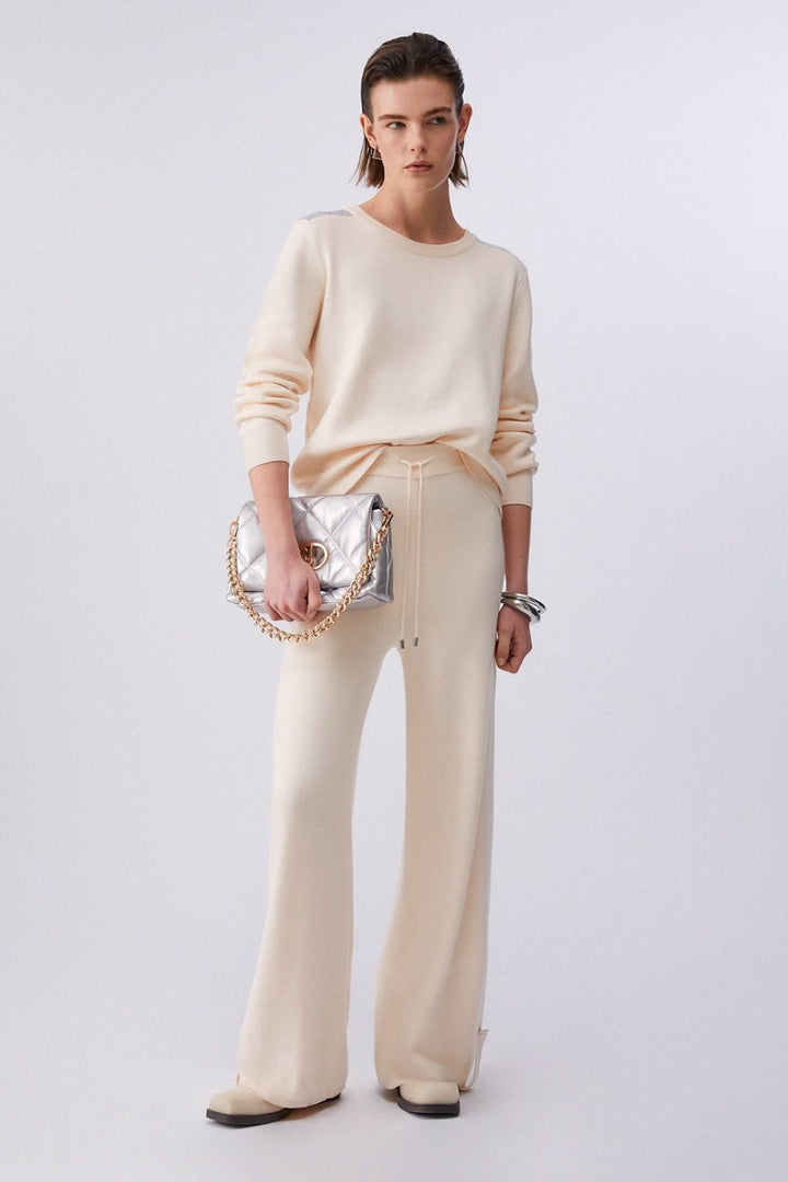 Pantalon jogging en maille à jambe large beige porté par une femme, avec taille élastique et cordon de serrage, allure décontractée élégante.