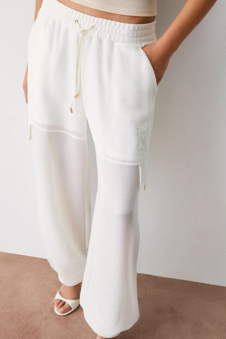 Pantalon jogging large à cordon blanc ample avec taille élastique, poches latérales et empiècement cargo pour style décontracté moderne.