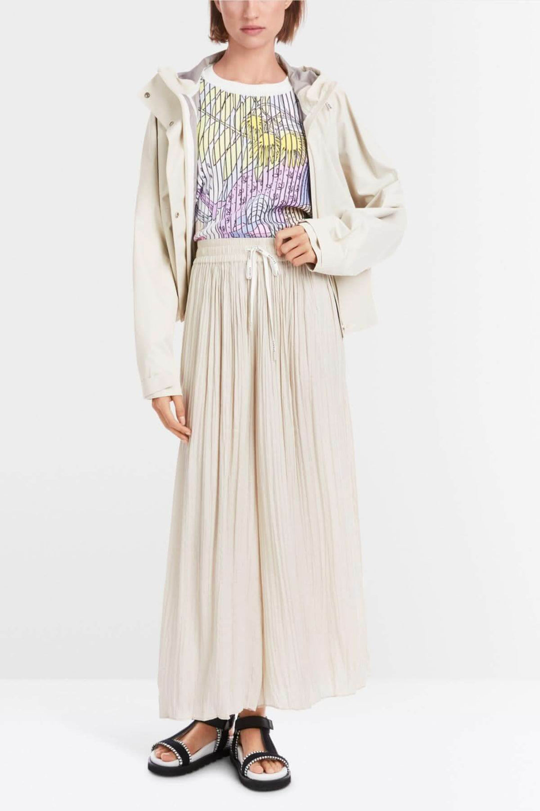 Femme portant un pantalon large WOLIN beige avec un haut graphique et une veste légère.