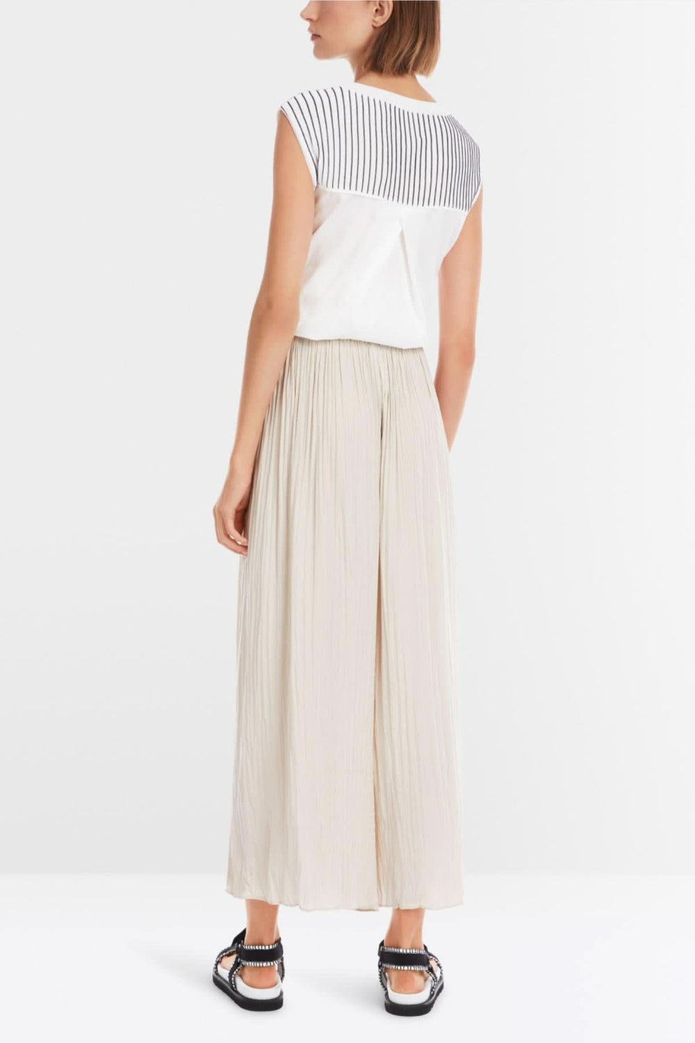 Femme portant un pantalon large Wolin beige, vue de dos, avec un haut à rayures. Style décontracté et élégant.