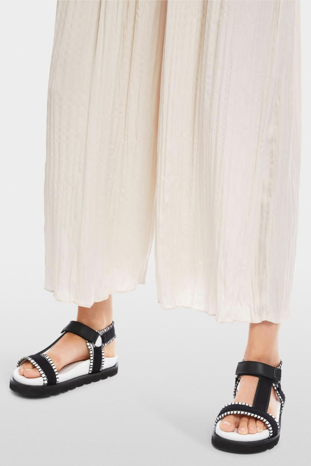 Pantalon large Wolin en tissu fluide avec sandales noires élégantes et confortables.