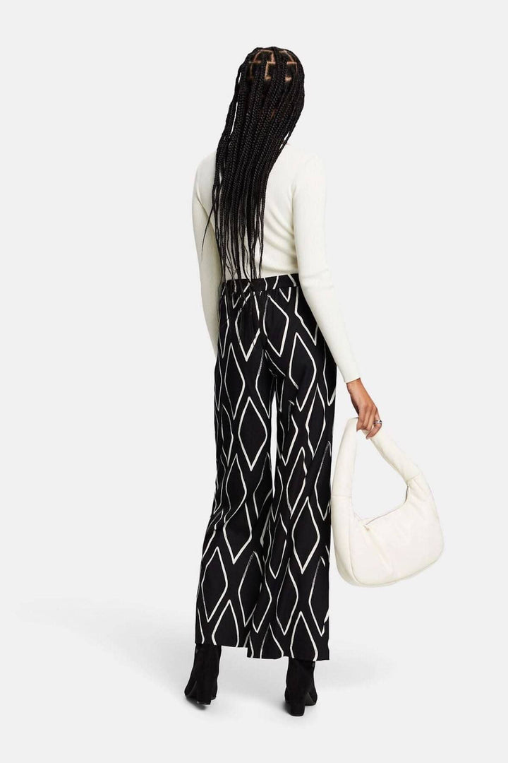 Pantalon large à enfiler imprimé losanges, porté avec un haut clair et un sac à main blanc.