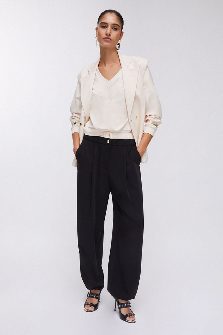 Femme portant un pantalon large à plis avec taille contrastante, alliant style élégant et confort.