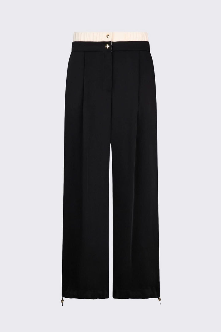Pantalon large à plis avec taille contrastante et boutons décoratifs, offrant une silhouette élégante et contemporaine.