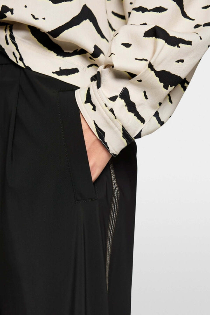 Pantalon léger WUXI avec poche latérale, coupe décontractée et bande sportive, porté avec une chemise imprimée.