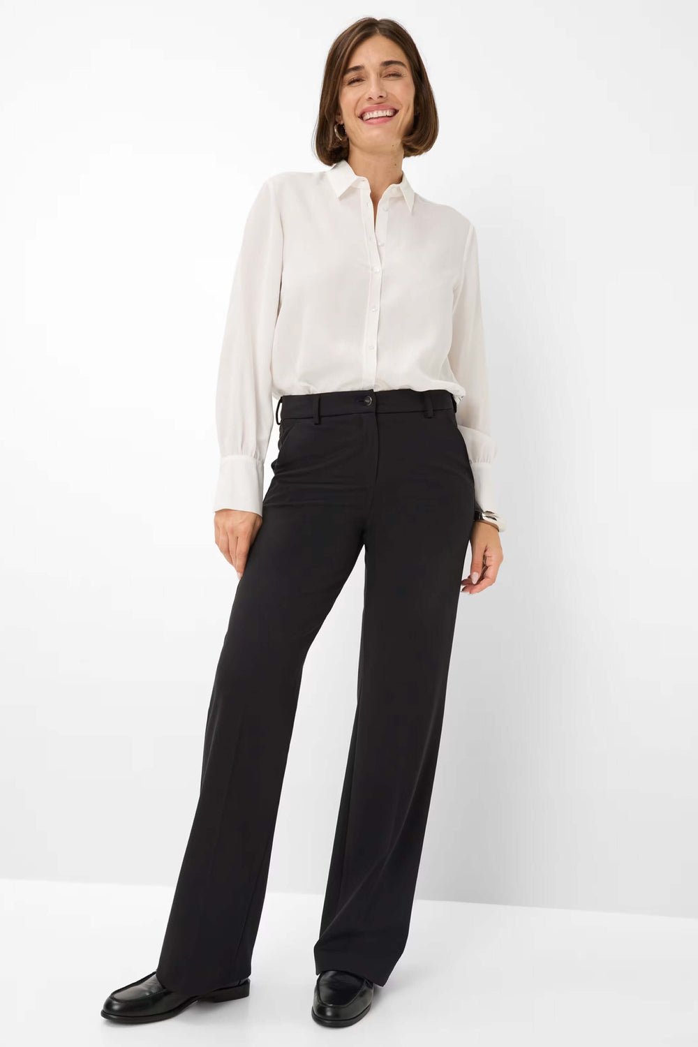 Femme portant un pantalon palazzo noir avec chemise blanche, alliant élégance et confort.