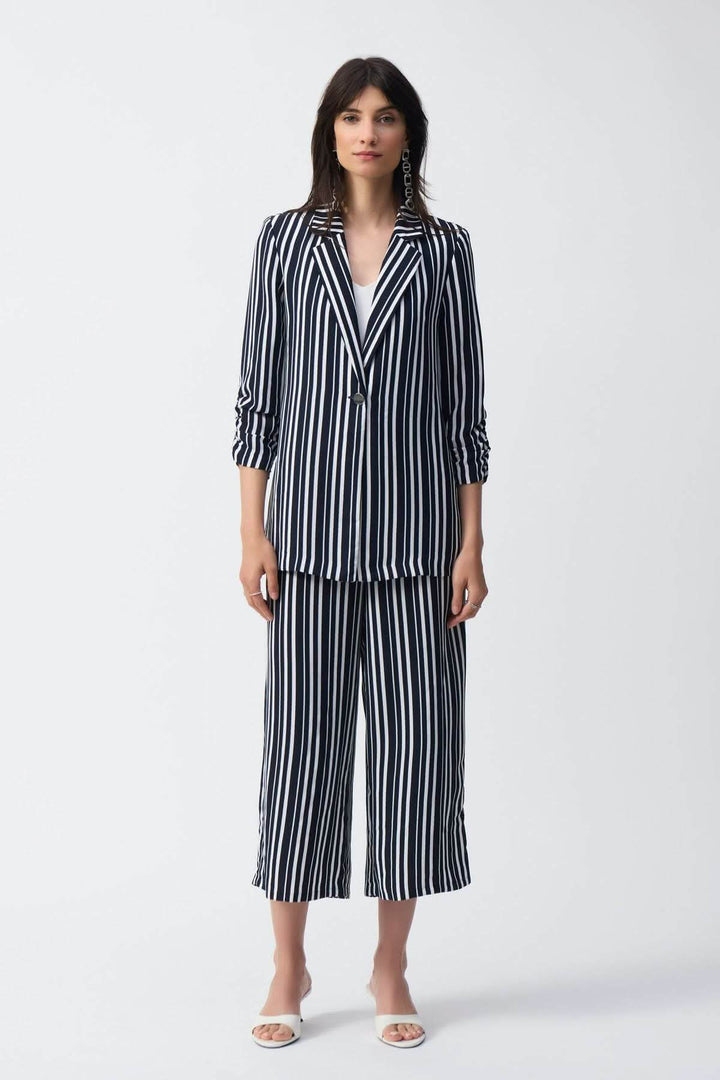 Femme portant un ensemble de pantalon rayé évasé et blazer à rayures, style moderne et décontracté.