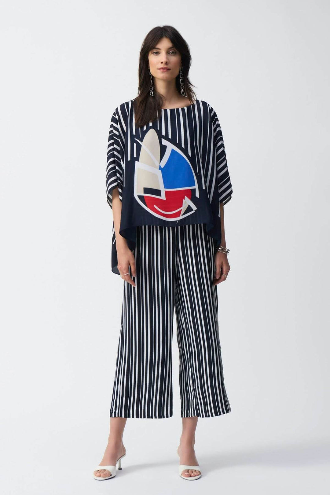 Femme portant une tenue à rayures évasées avec un haut graphique et des pantalons modernes, style décontracté.