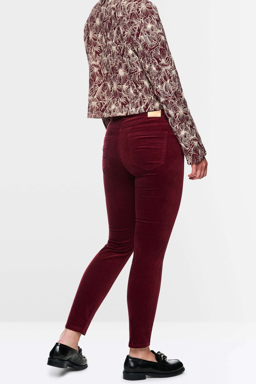 Pantalon taille basse en velours bordeaux, coupe ajustée mise en valeur avec un haut moderne.