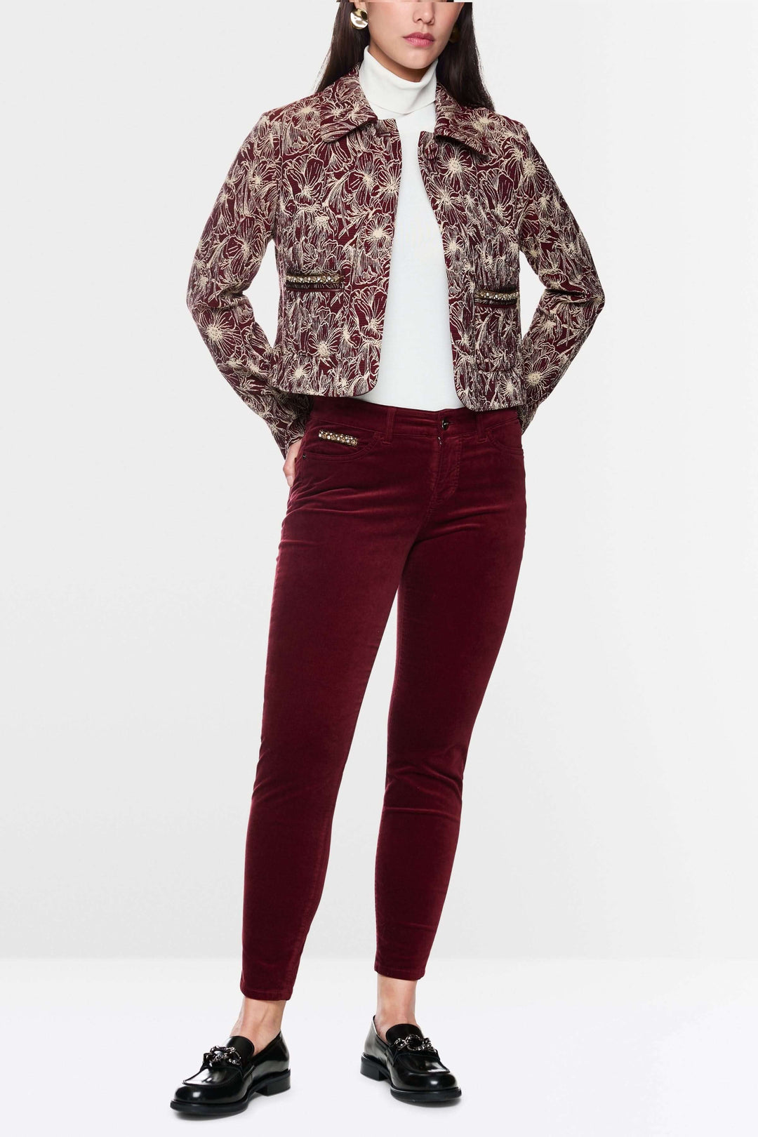 Femme en pantalon velours taille basse rouge et veste imprimée, look chic et moderne.