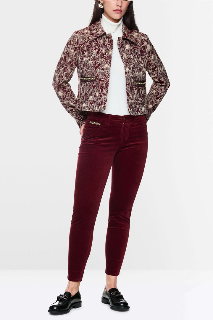 Femme en pantalon velours taille basse rouge et veste imprimée, look chic et moderne.