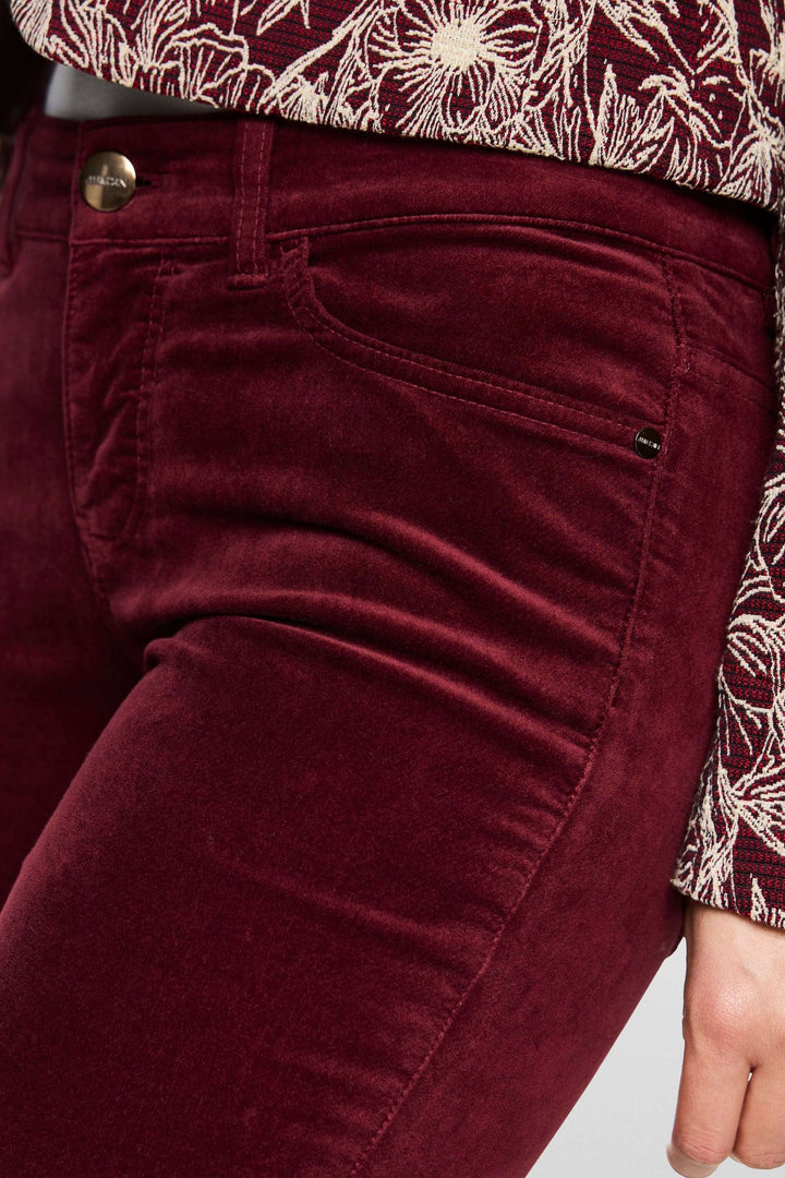 Pantalon taille basse en velours bordeaux, coupe ajustée près du corps avec poches et détails élégants.