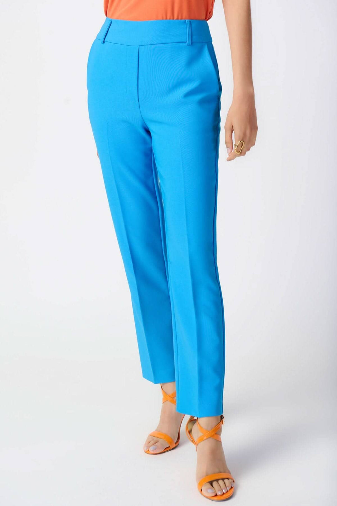 Pantalon tailleur droit bleu, taille haute, coupe décontractée et poches latérales, porté avec un top orange.