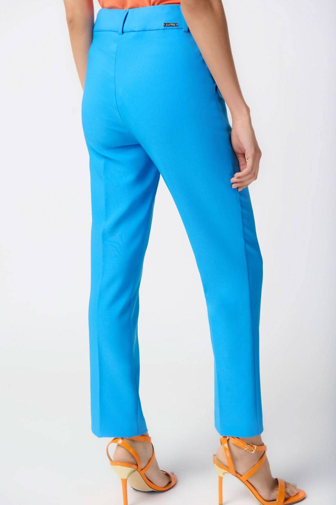 Pantalon tailleur droit bleu, taille haute, coupe décontractée avec poches latérales, porté avec des sandales orange.