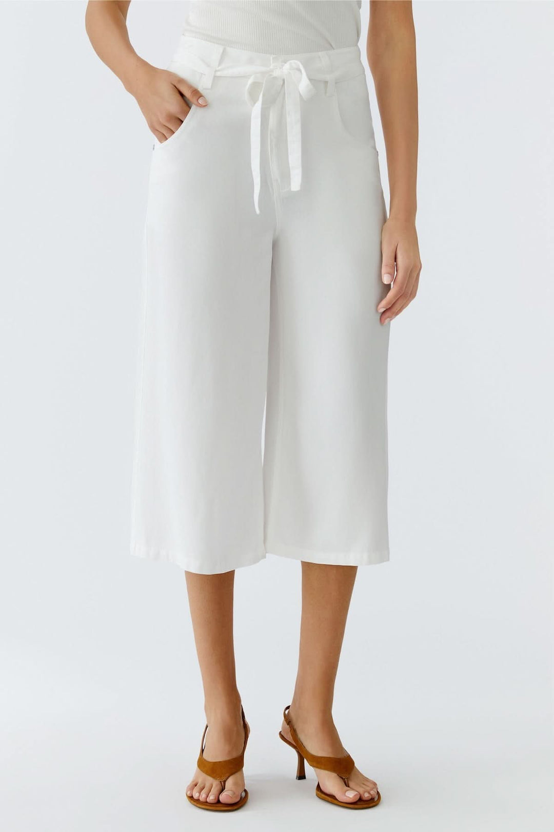 Pantalon trois quarts à taille nouée blanc avec coupe large et fluide, parfait pour la saison estivale, porté avec des sandales.