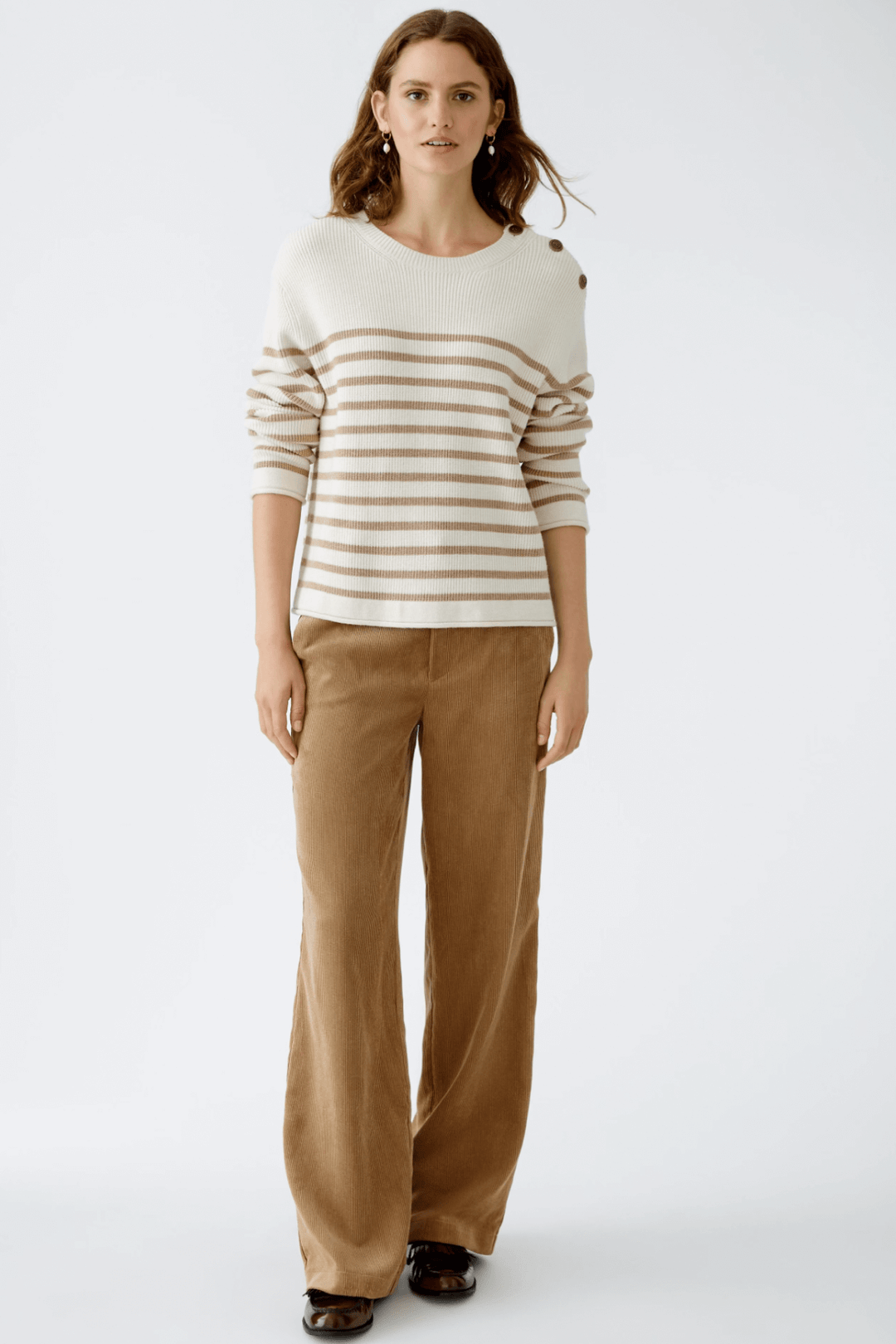 Femme en pantalon velours côtelé beige et pull rayé, look décontracté et élégant.