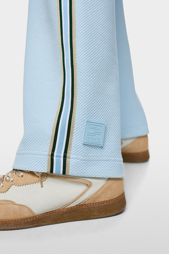 Gros plan sur le bas des pantalons à coupe large WASHINGTON avec bandes contrastantes et sneakers beiges.